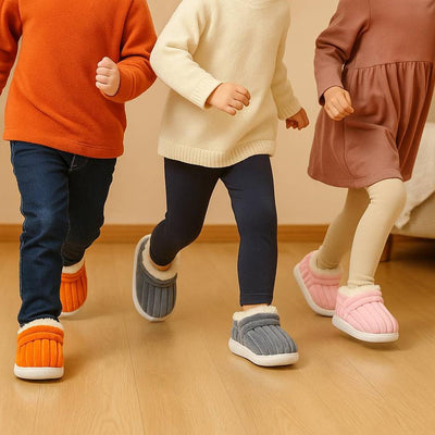 Three children running across wood floor wearing orange, gray and pink winter slippers