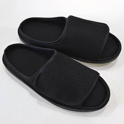 Pair of black mesh open-toe slippers on white background