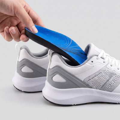 Hand inserting blue arch support insole into a running shoe