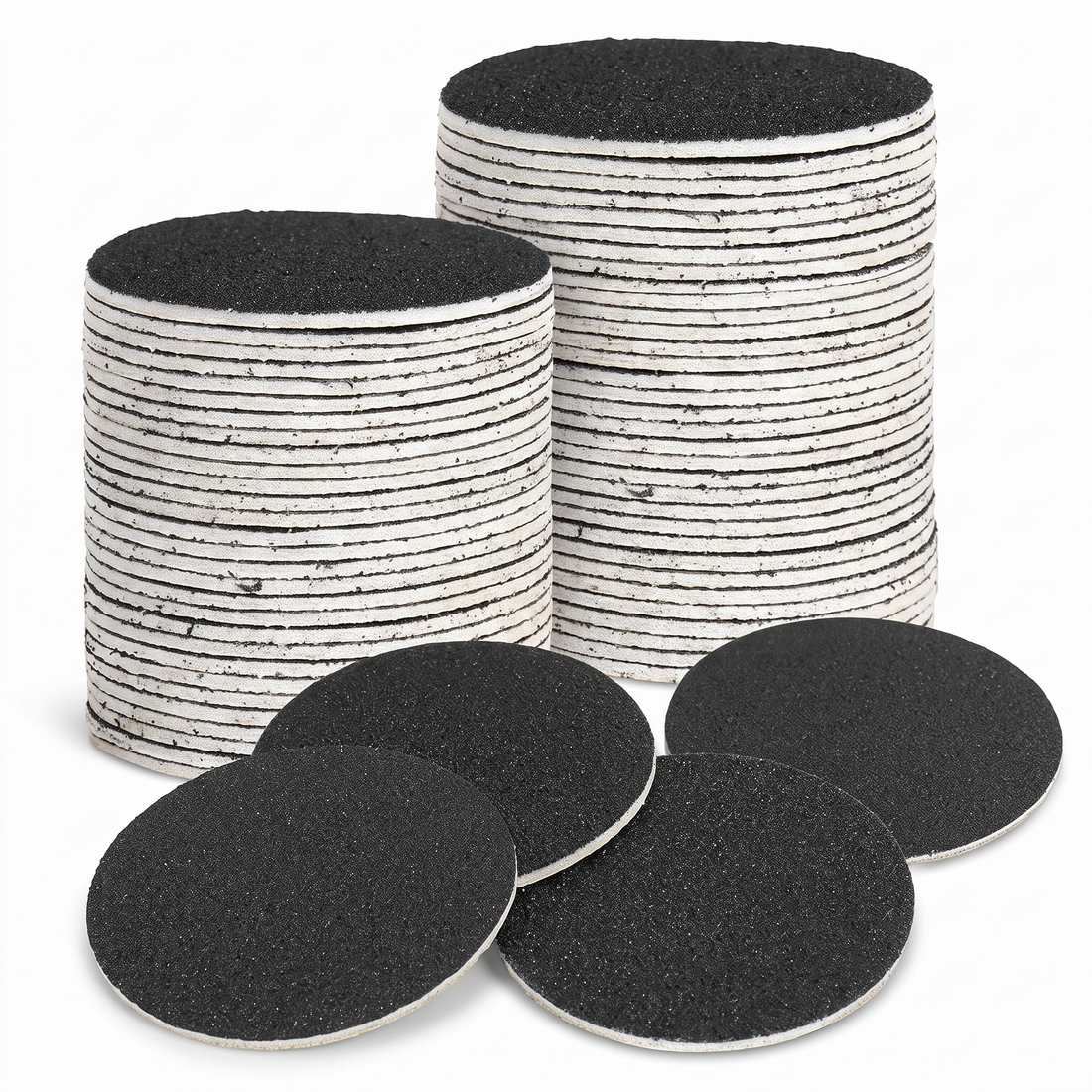 Stacked black sandpaper foot file refill discs on white background