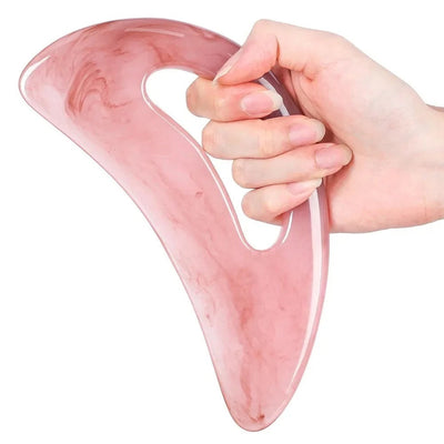 Hand gripping pink Gua Sha tool through its thumb hole