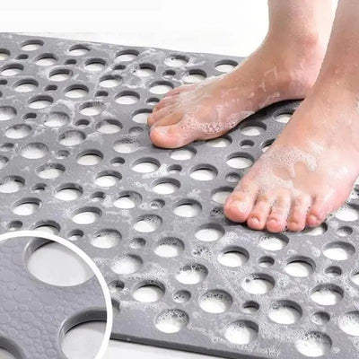 Bare feet standing on grey non-slip bath mat showing suction cup detail