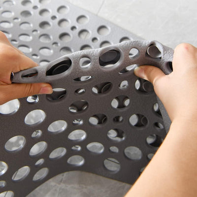 Hands bending grey non-slip bath mat to show flexibility