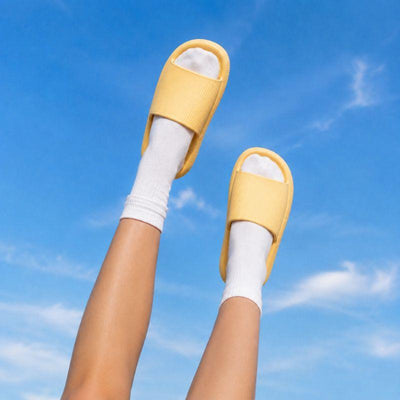 Yellow slide slippers worn on raised legs showing thick cushion sole