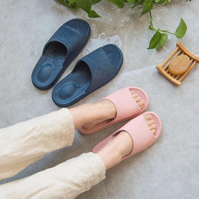 Person wearing pink heel slippers next to blue pair on floor