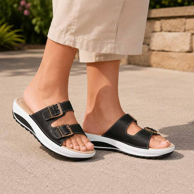 Woman wearing black wedge sandals with buckle straps outdoors